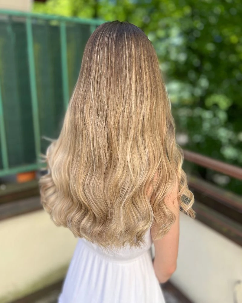 Dlouhé vlnité vlasy s balayage efektem, foceno zvenku.